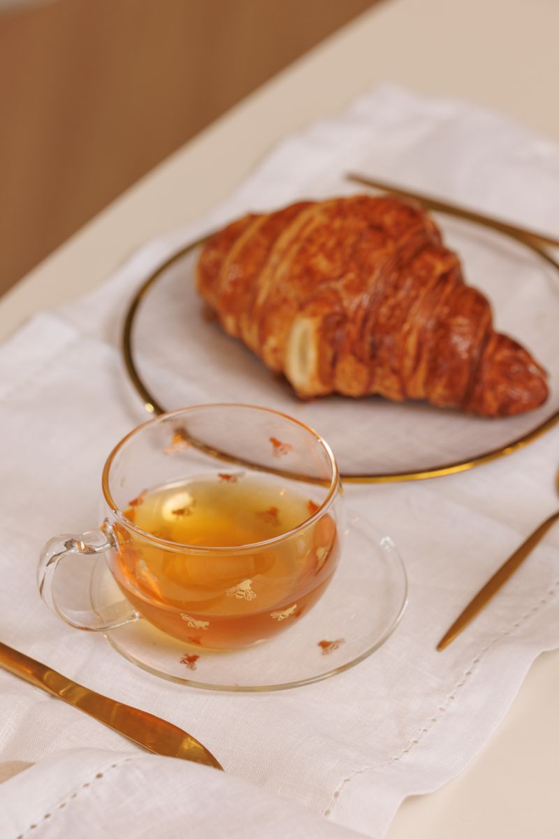 Croissant e xícara de chá dourado sobre a mesa