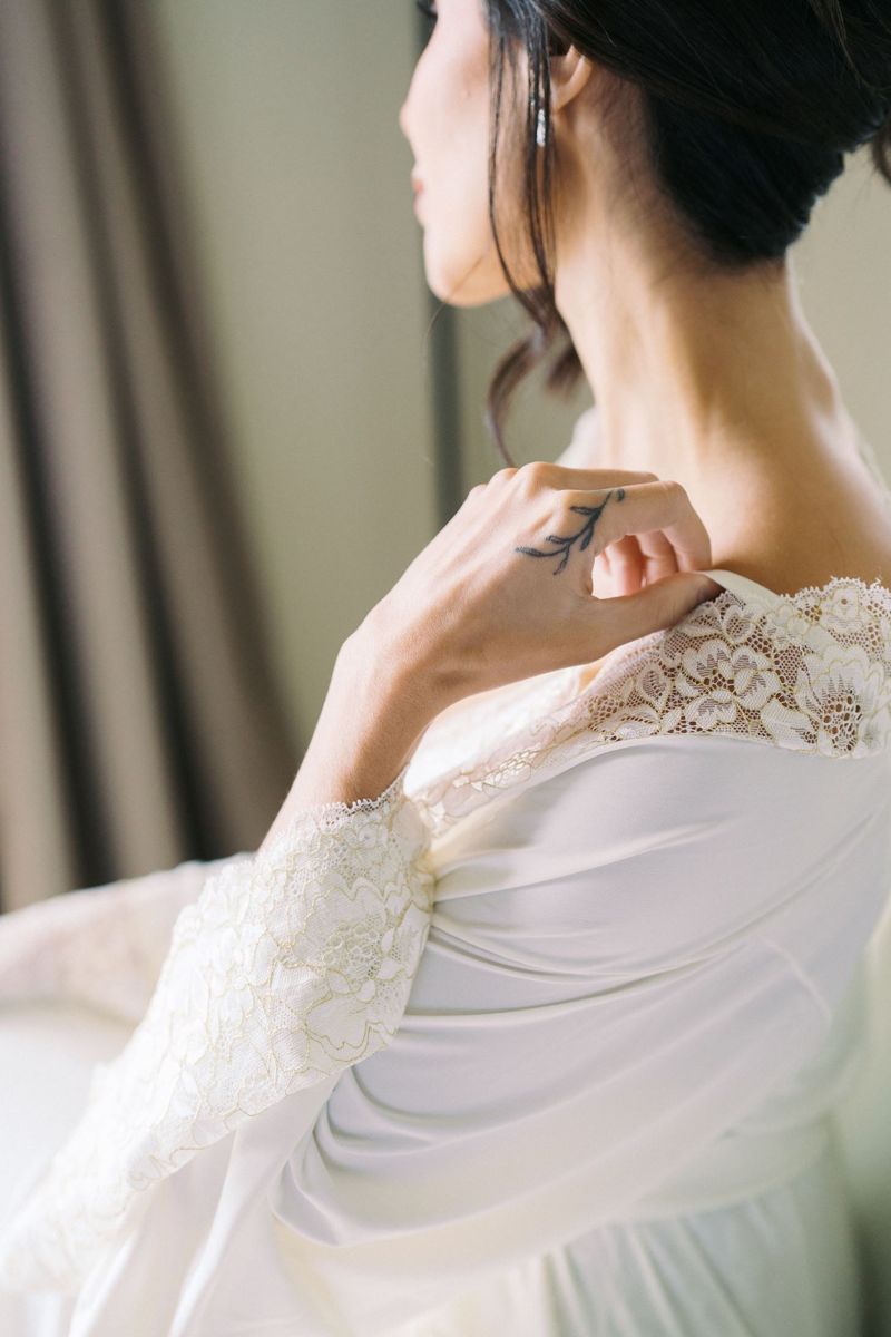 Noiva vestindo robe branco com renda de fios dourados no ombro